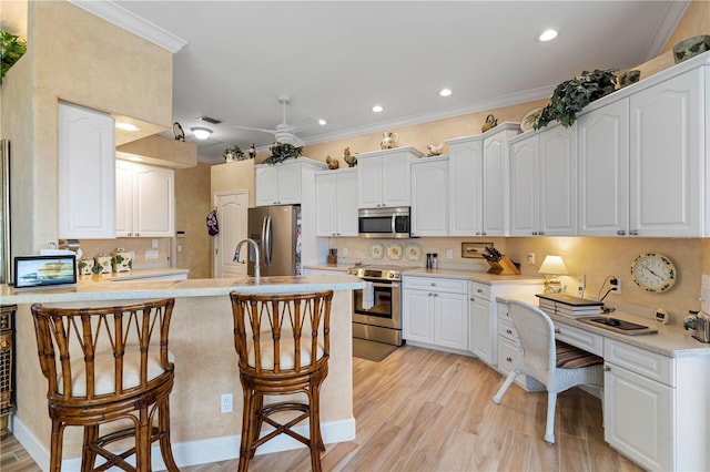 kitchen with a breakfast bar area, white cabinets, stainless steel appliances, and light hardwood / wood-style floors