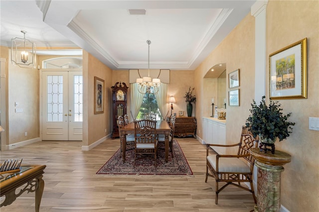 dining room featuring light hardwood / wood-style floors, a tray ceiling, ornamental molding, and an inviting chandelier