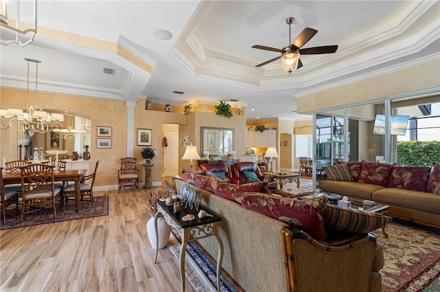 living room with crown molding, a raised ceiling, light hardwood / wood-style flooring, and ceiling fan with notable chandelier