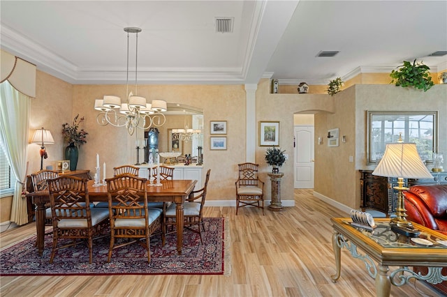 dining space with ornamental molding, light hardwood / wood-style flooring, and an inviting chandelier