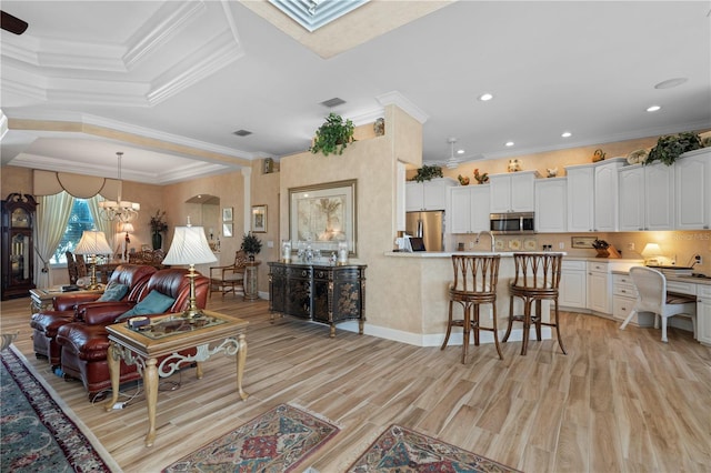 living room with light hardwood / wood-style floors, crown molding, a chandelier, and sink