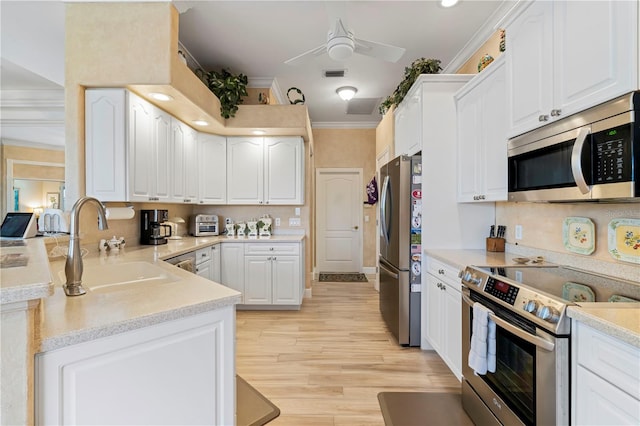 kitchen with white cabinets, stainless steel appliances, sink, and light wood-type flooring