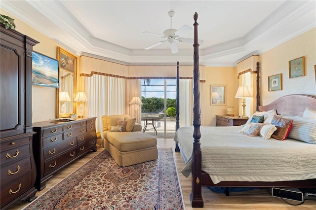 bedroom featuring access to outside, a tray ceiling, ceiling fan, light hardwood / wood-style floors, and crown molding