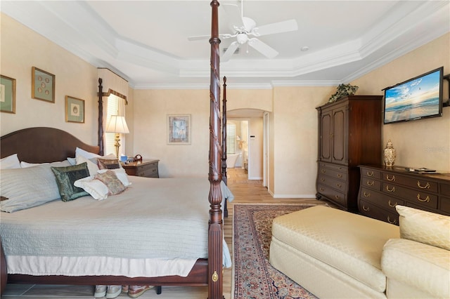 bedroom with hardwood / wood-style floors, a raised ceiling, crown molding, and ceiling fan