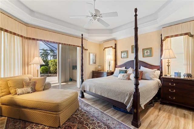 bedroom with crown molding, light hardwood / wood-style flooring, a tray ceiling, and ceiling fan