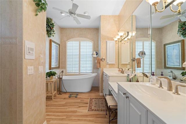 bathroom featuring vanity, ceiling fan with notable chandelier, a bathing tub, and hardwood / wood-style floors