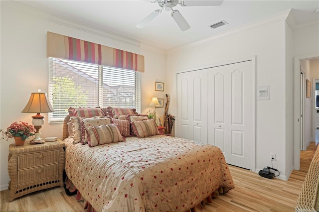 bedroom featuring ornamental molding, a closet, light wood-type flooring, and ceiling fan