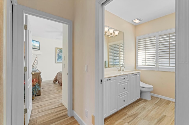 bathroom with vanity, a notable chandelier, toilet, and wood-type flooring