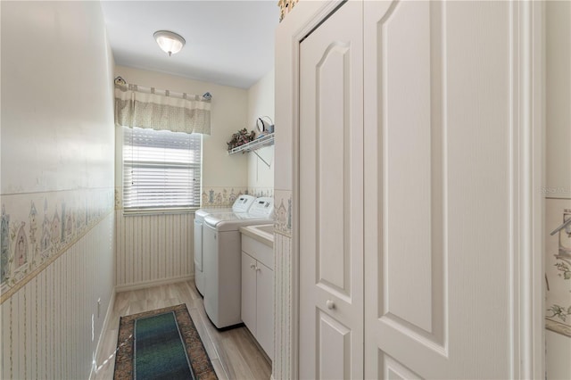 washroom featuring light hardwood / wood-style flooring, separate washer and dryer, and cabinets