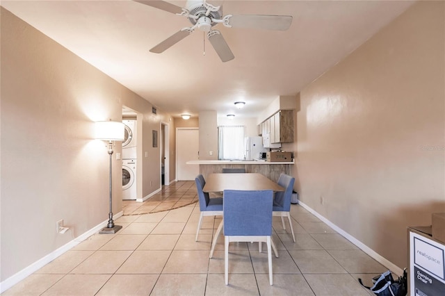 tiled dining area with ceiling fan and stacked washer / drying machine