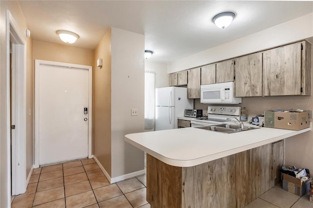 kitchen with light tile patterned flooring, kitchen peninsula, white appliances, and sink