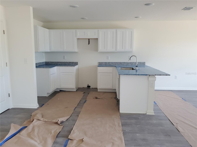 kitchen featuring white cabinets, hardwood / wood-style flooring, dark stone counters, and sink