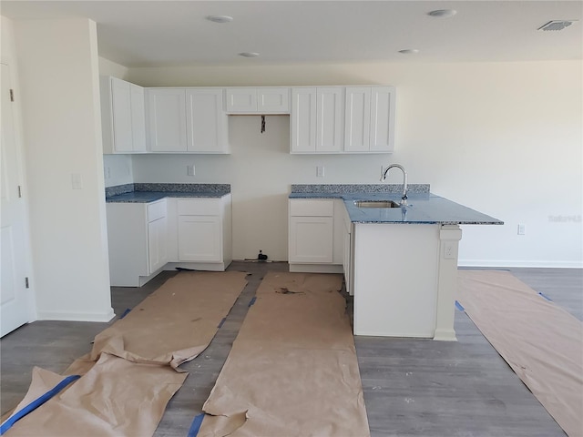 12966 SE 53rd Ave, Belleview, FL 34420 - kitchen with a peninsula, white cabinetry, a sink, and baseboards