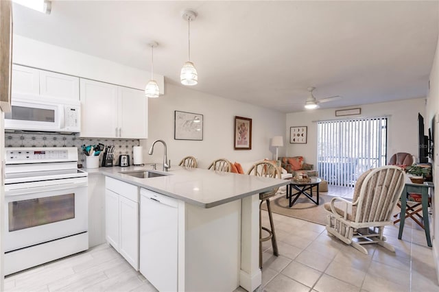 kitchen featuring white appliances, white cabinets, sink, and kitchen peninsula