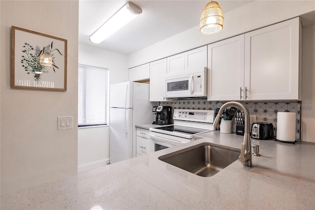 kitchen featuring tasteful backsplash, white appliances, light stone counters, sink, and white cabinets