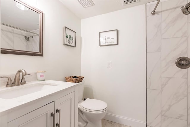 bathroom with vanity, toilet, and tiled shower