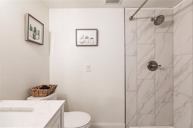 bathroom featuring vanity, tiled shower, and toilet