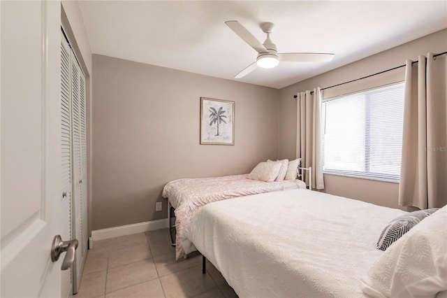 tiled bedroom with ceiling fan and a closet