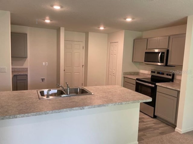 kitchen featuring stainless steel appliances, sink, and gray cabinetry