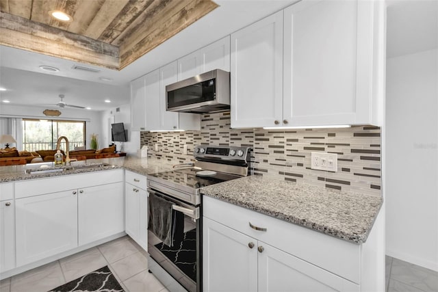 kitchen featuring light stone counters, sink, tasteful backsplash, white cabinetry, and stainless steel appliances