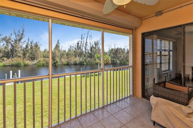 unfurnished sunroom featuring ceiling fan and a water view