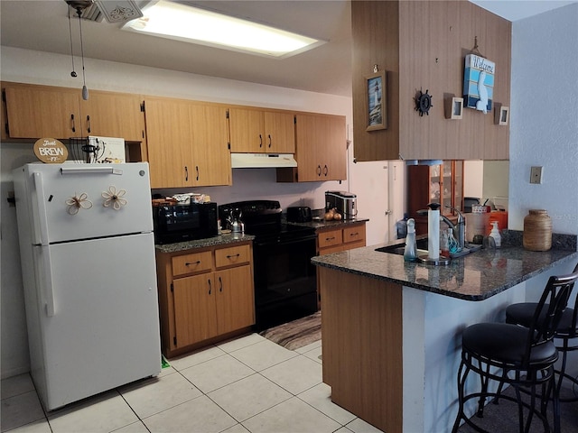 kitchen with dark stone counters, black appliances, light tile patterned flooring, and kitchen peninsula