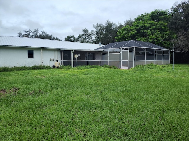 rear view of house with a yard and a lanai