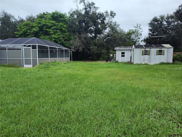 view of yard featuring glass enclosure and an outbuilding