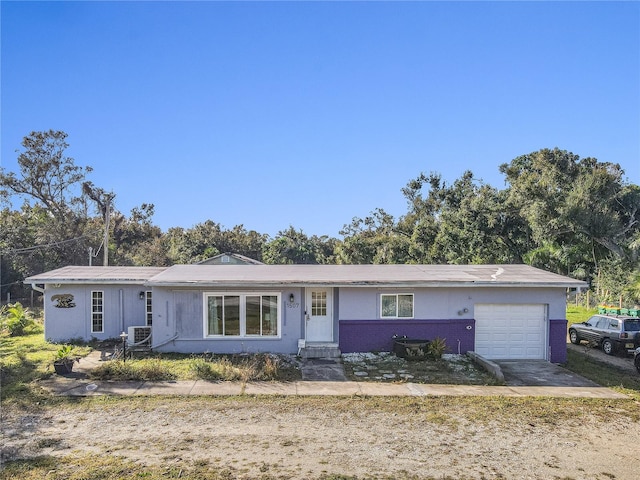 ranch-style home featuring central AC unit and a garage