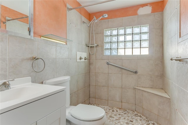 bathroom with tiled shower, vanity, and toilet