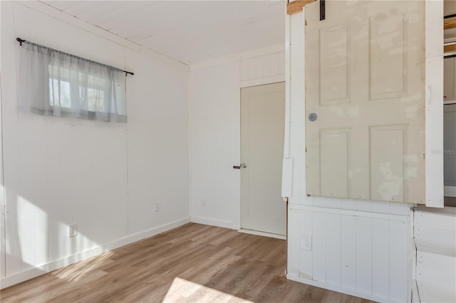 unfurnished room with crown molding, a barn door, and light wood-type flooring