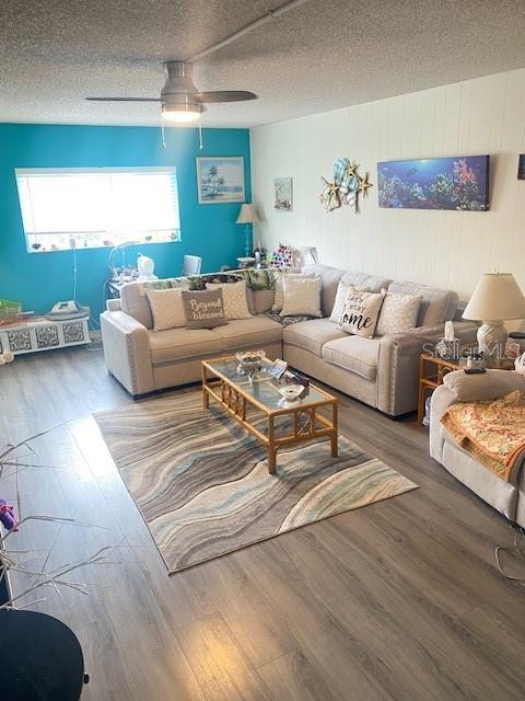 living room with ceiling fan, hardwood / wood-style floors, and a textured ceiling