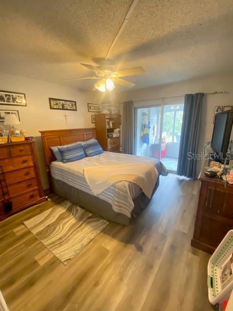 bedroom with a textured ceiling, access to exterior, light wood-type flooring, and ceiling fan