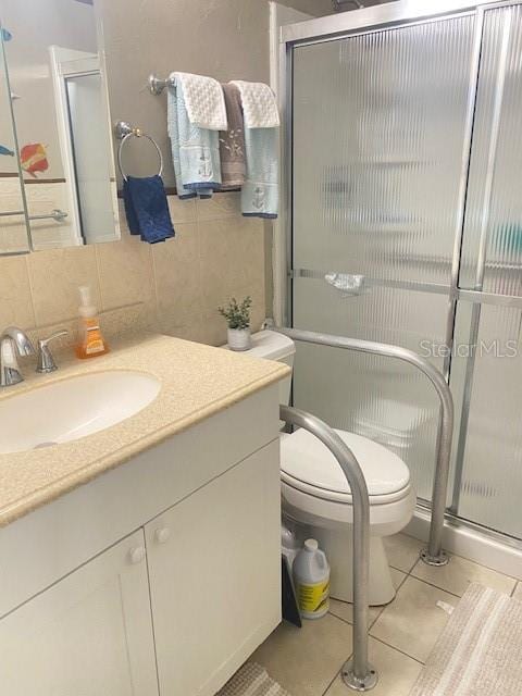 bathroom featuring vanity, a shower with door, tile patterned flooring, toilet, and backsplash