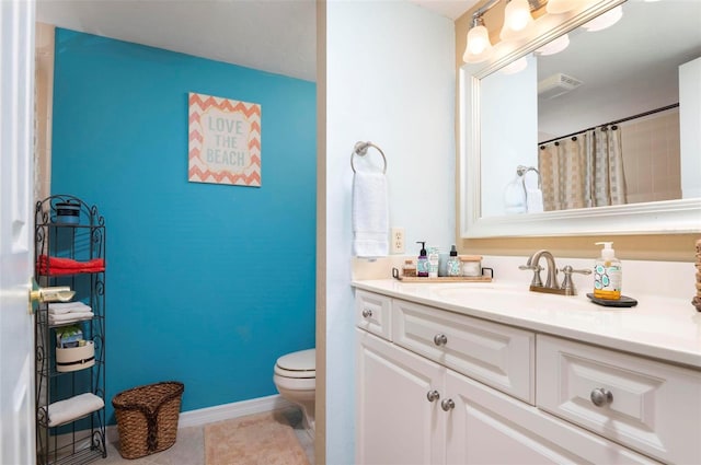 bathroom with toilet, vanity, and tile patterned floors