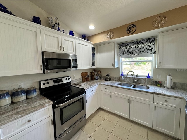 kitchen with lofted ceiling, appliances with stainless steel finishes, sink, and white cabinetry