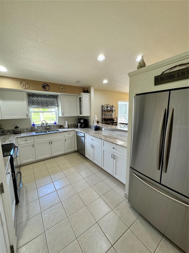 kitchen featuring light tile patterned floors, appliances with stainless steel finishes, sink, and white cabinetry