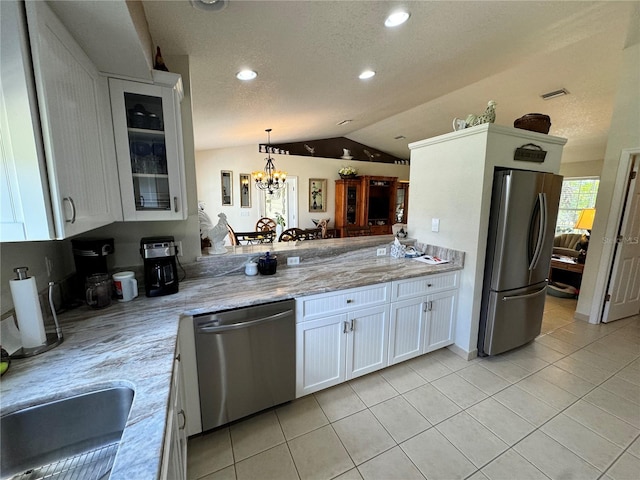 kitchen with lofted ceiling, pendant lighting, white cabinets, and appliances with stainless steel finishes