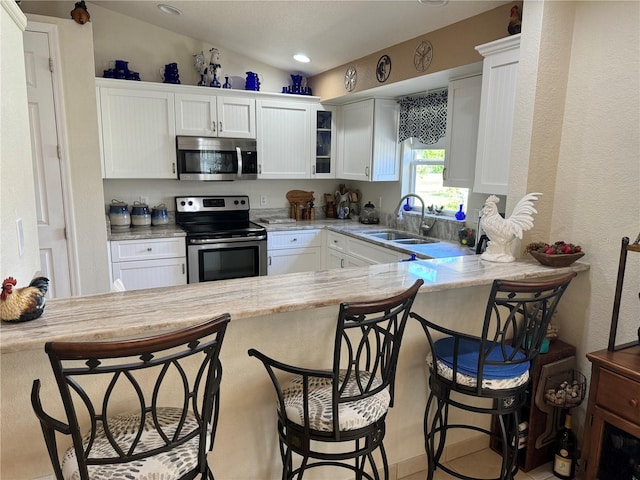 kitchen with white cabinets, appliances with stainless steel finishes, sink, and vaulted ceiling