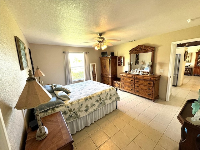 bedroom featuring ceiling fan, light tile patterned floors, and a textured ceiling