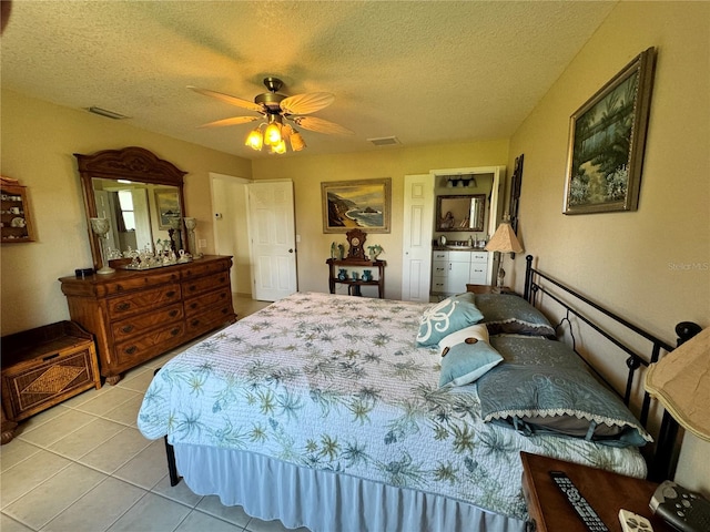 bedroom with ceiling fan, light tile patterned floors, and a textured ceiling