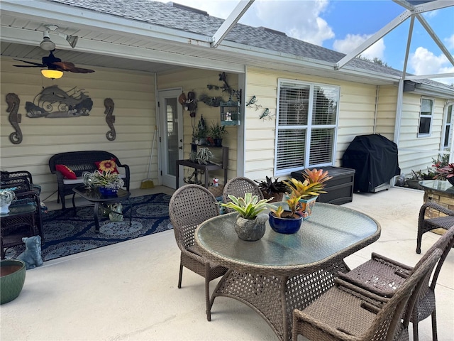 view of patio with ceiling fan, a grill, and glass enclosure