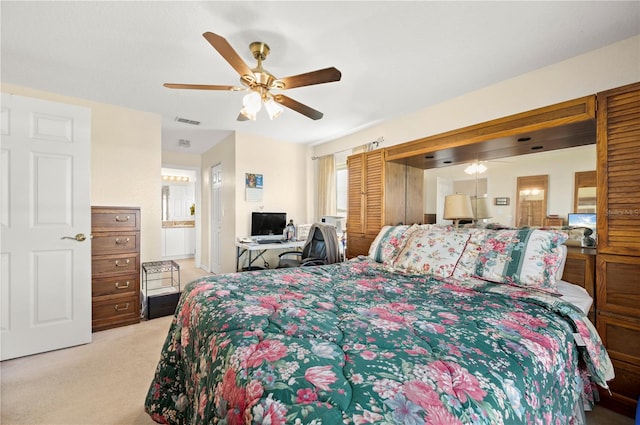 bedroom featuring ensuite bathroom, light colored carpet, and ceiling fan