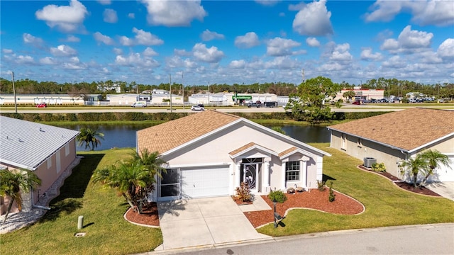 view of front of house with a front yard, a garage, and a water view