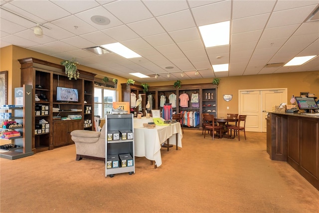 carpeted living room featuring a drop ceiling