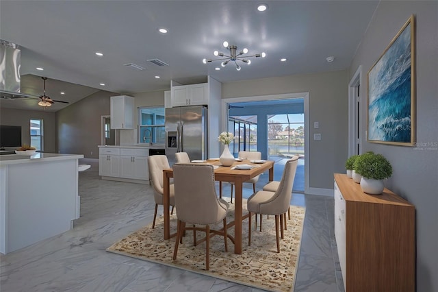 dining space with sink, ceiling fan with notable chandelier, and vaulted ceiling