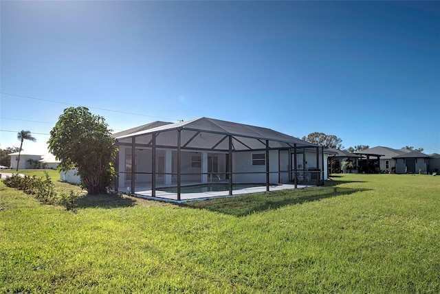 rear view of property featuring a lawn, an outdoor pool, a lanai, and a patio area