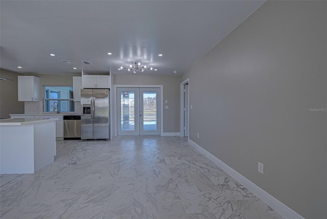 kitchen with vaulted ceiling, sink, stainless steel appliances, french doors, and white cabinetry