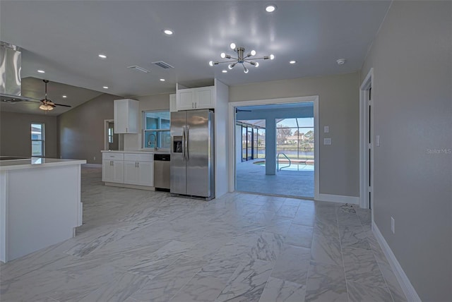 kitchen featuring ceiling fan with notable chandelier, sink, stainless steel appliances, white cabinets, and lofted ceiling