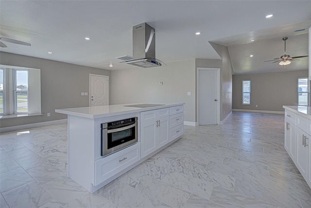 kitchen featuring ventilation hood, white cabinets, an island with sink, and oven